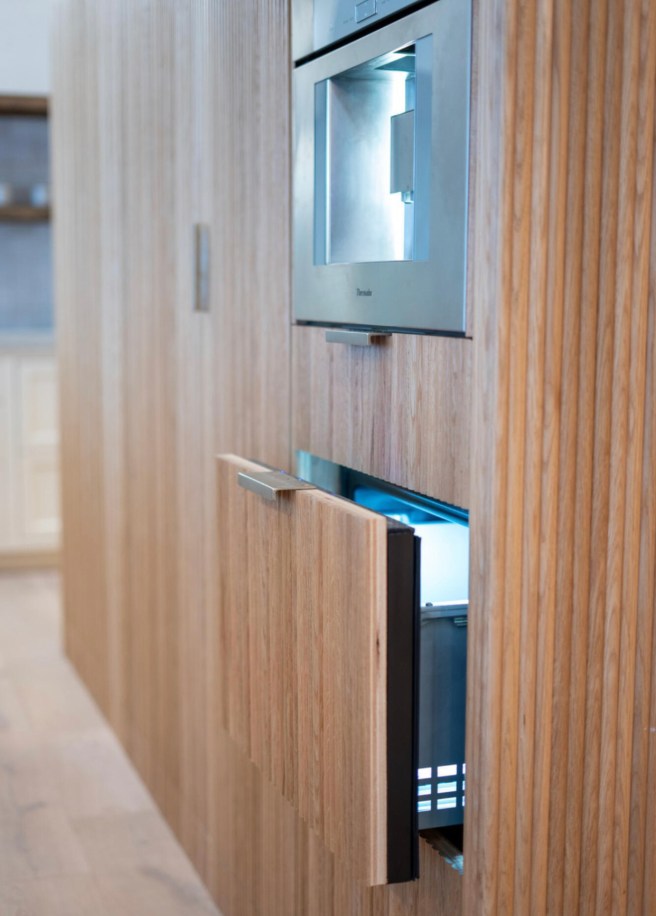 A thermador Fridge drawer holds cream for the family's coffee in a fluted oak kitchen cabinet